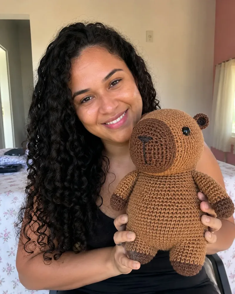 Clienta sosteniendo una capibara de crochet hecha por ella.
